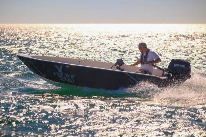 A man riding an Enlightened Boating boat at sunset